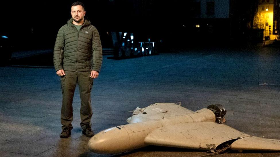 President Volodymyr Zelensky stands beside a downed drone