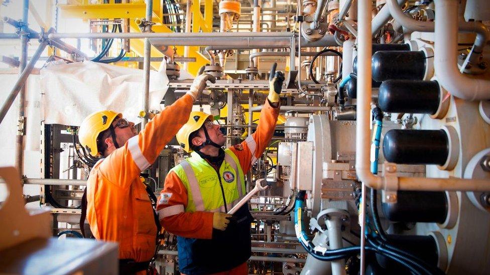 Employees gesture on an oil and gas platform on the North Sea, about 45 miles (70 kilometres) east of the Aberdeen