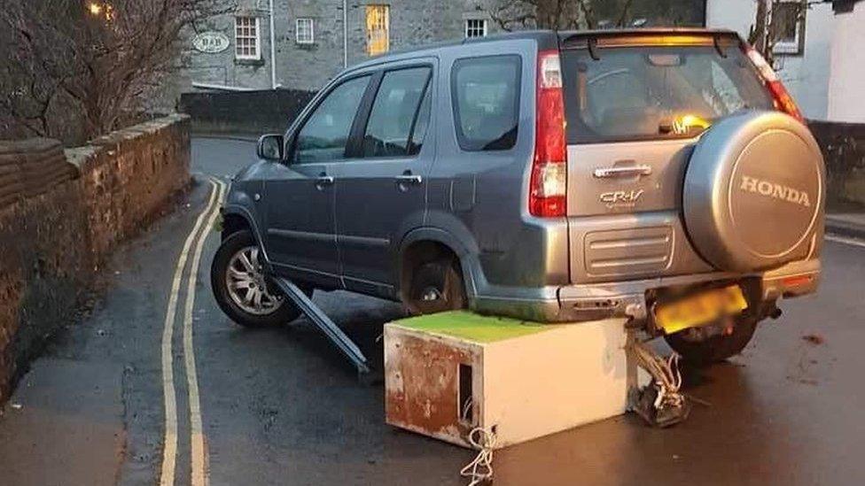 ATM wedged beneath parked car