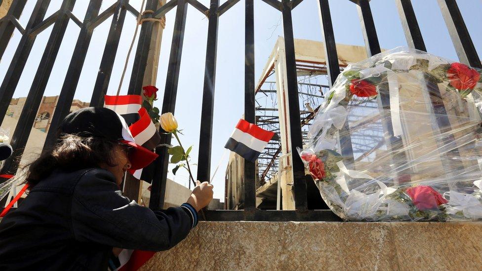 A Yemeni girl puts roses in front of a destroyed funeral hall, a week after Saudi-led airstrikes hit it, during a rally in solidarity and honour of the victims of the 8 October airstrikes, in Sanaa, Yemen, on 15 October 2016