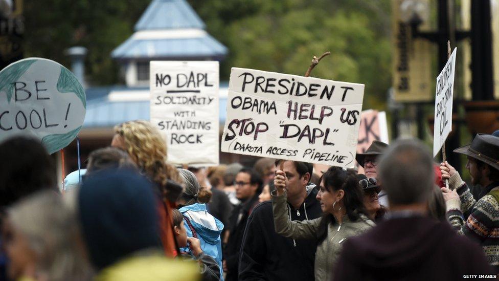 This is a photo showing a campaign placard that says, "President Obama help us stop DAPL".