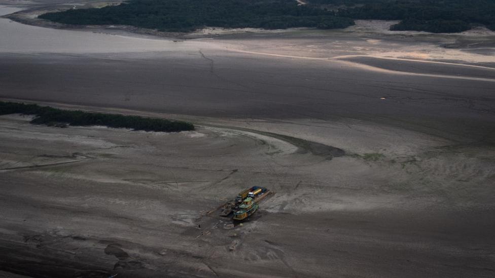 Aerial view of raft with vehicles, gas and supplies gets stuck in the dry bed of the Rio Negro on October 3, 2023 in Manaus, Brazil.