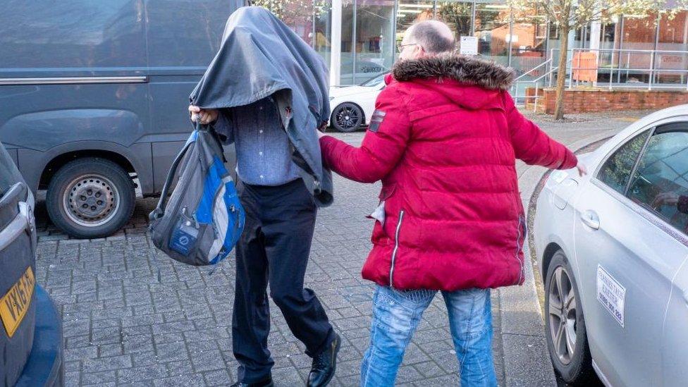 Timothy Schofield holding a coat over his head