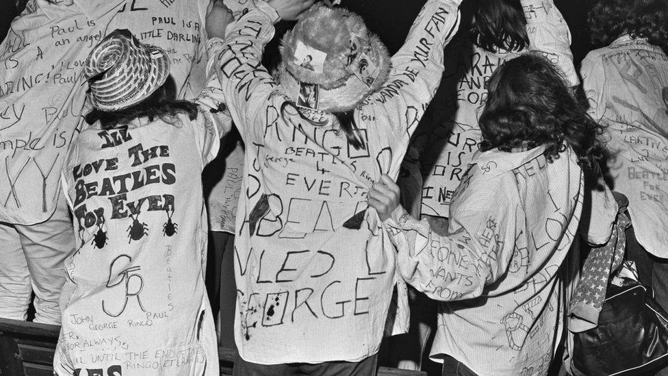 Fans with positive messages for The Beatles written on their clothes, taken in the 60s