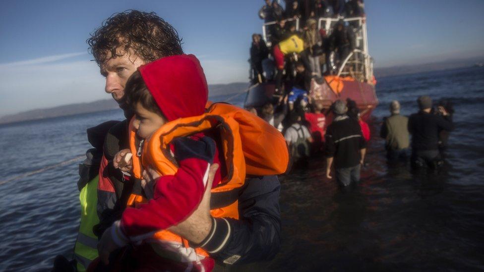 A child is helped ashore on Lesbos