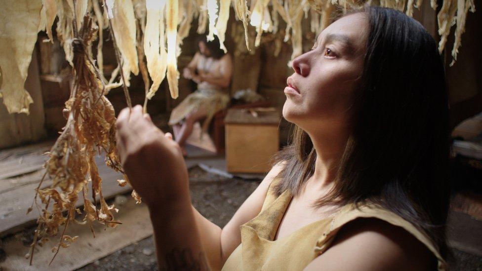 Hlaaya, the mother of the boy who dies, drying leaves to prepare them for weaving