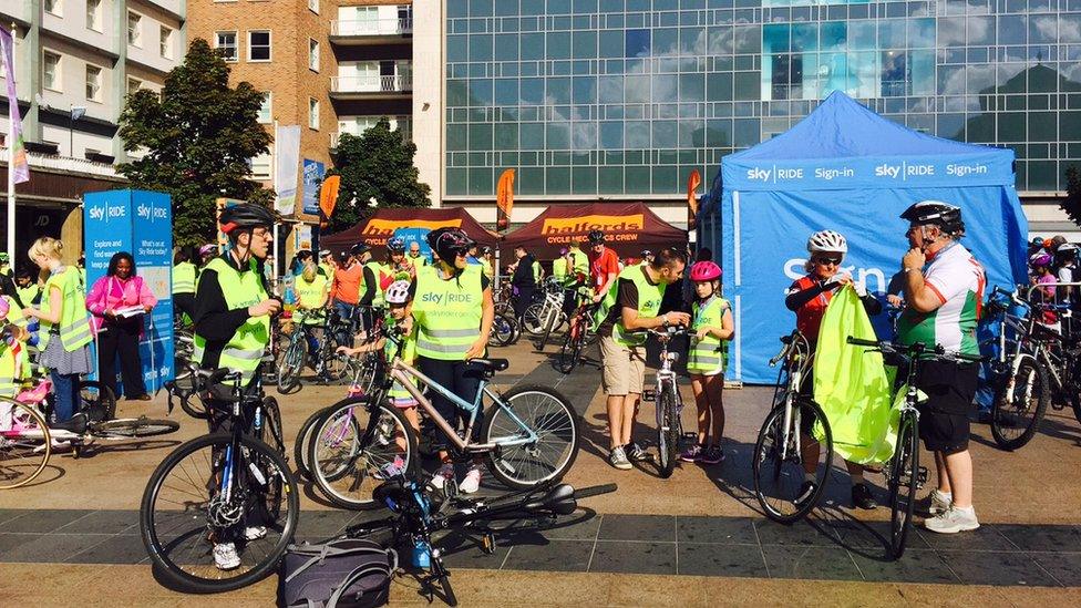 Cyclists standing with their bikes beside tents