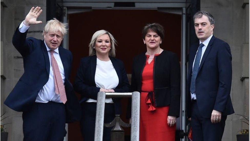 Boris Johnson waving and standing next to the first and deputy first ministers and NI Secretary Julian Smith