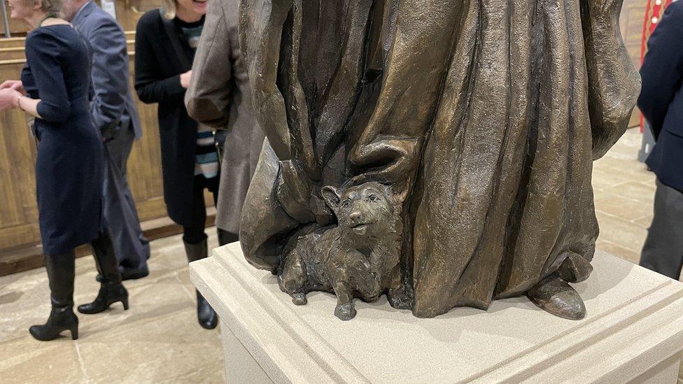 A Corgi dog next to the Queen's feet in the bronze statue