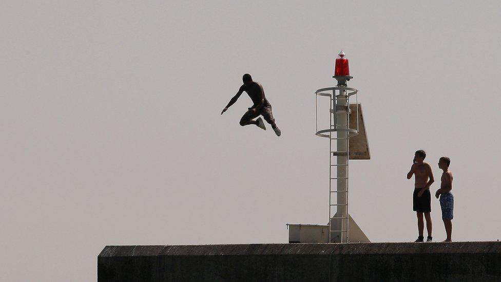 Man jumping off rocks into the sea