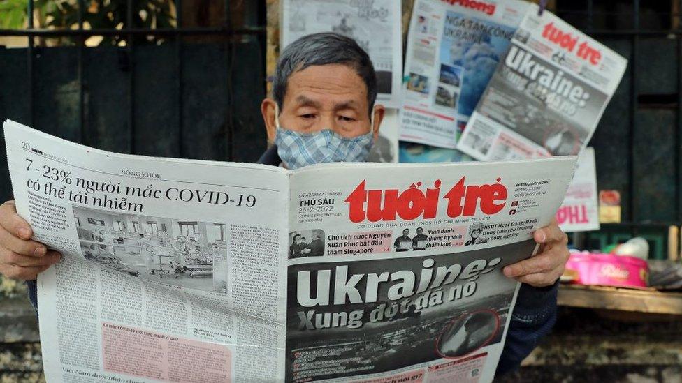 A man reads a Vietnamese newspaper featuring front page coverage of the Russian invasion of Ukraine at a stall in Hanoi on February 25, 2022