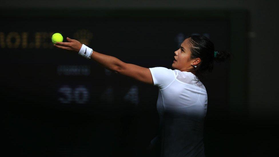 emma raducanu throws a tennis ball up into the air