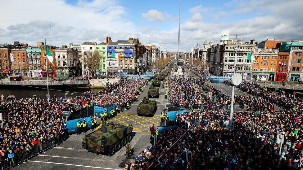 Spectators watch the largest military parade pass over O'Connell Bridge