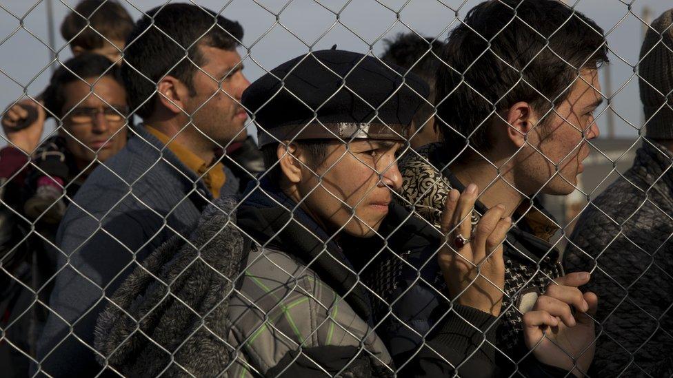 Afghans wait to board a bus on the Greek border after Macedonia refuses to let them enter