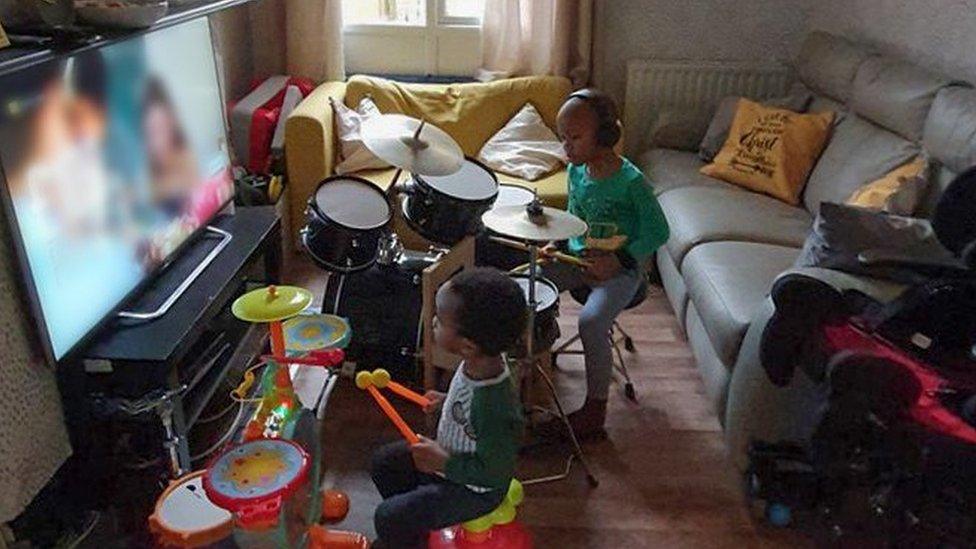 Front room with two children playing on drum sets in front of the TV