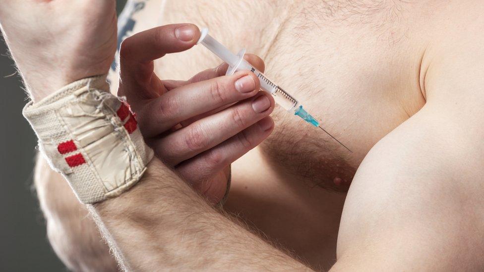 Muscular man injecting steroids