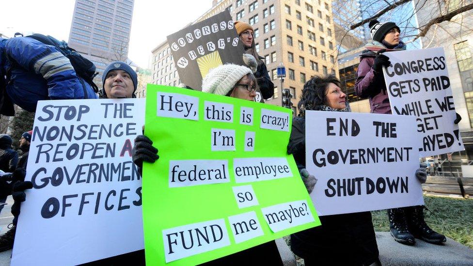 Demonstrator hold signs during a protest rally by government workers and concerned citizens against the government shutdown on Friday, January 11, 2019