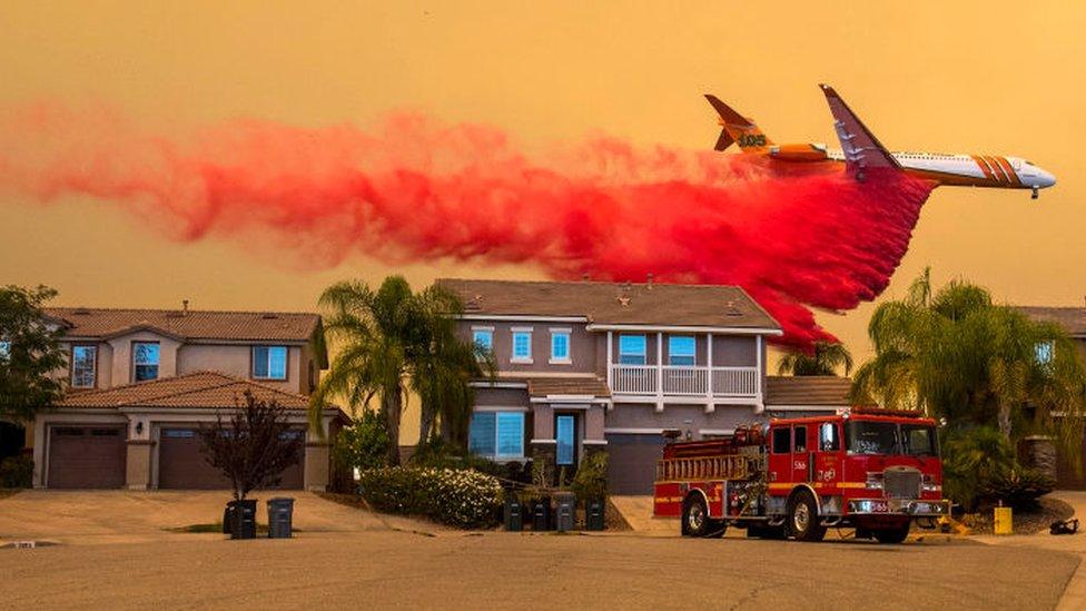 A plane drops retardant over a home