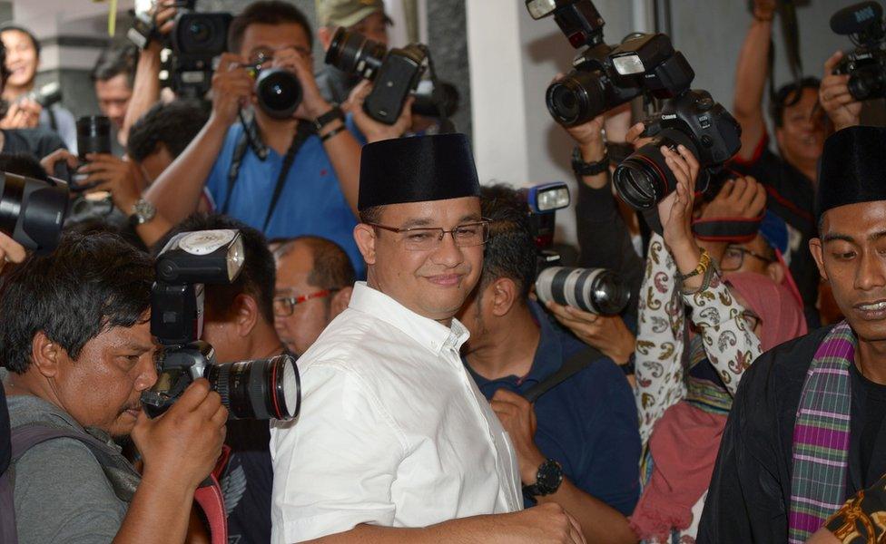 Candidate for Jakarta governor, Anis Baswedan (C) is surrounded by journalists as he arrives at a poll station in Jakarta on 19 April 2017.