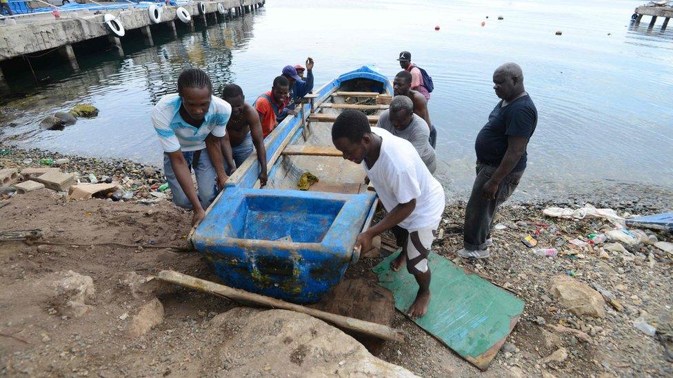 Fishermen pull a boat out of the water at the waterfront before the arrival of Hurricane Matthew in Kingston, Jamaica on 1 October