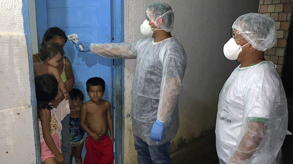 Handout photo released by the Special Secretariat for Indigenous Health (Sesai) showing a worker checking the temperature of members of the Tikuna group in Lago Grande, Amazonas state, Brazil (2 April 2020)