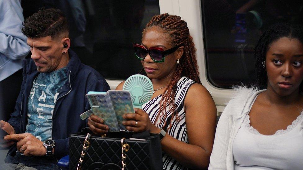 A commuter with a portable handheld fan on a Jubilee line train