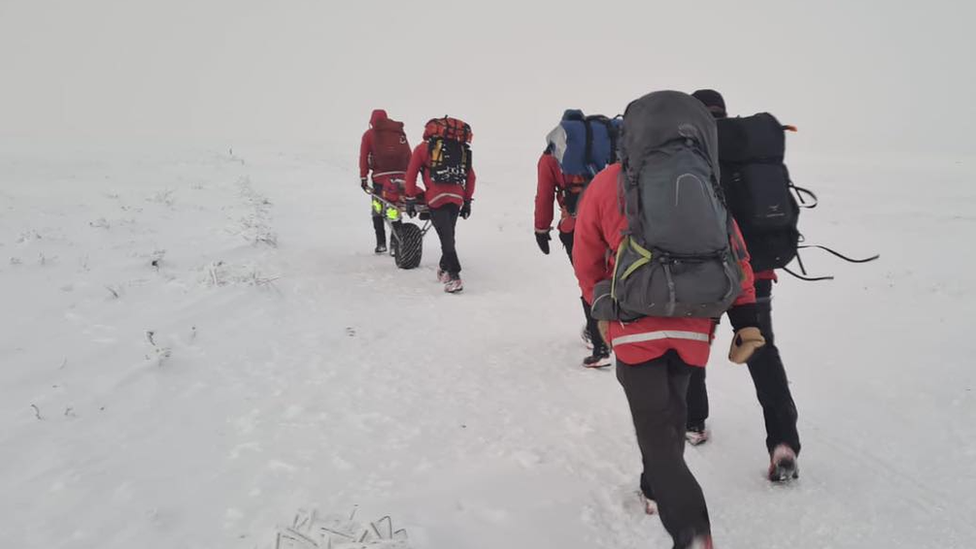 Rescuers walk through snow