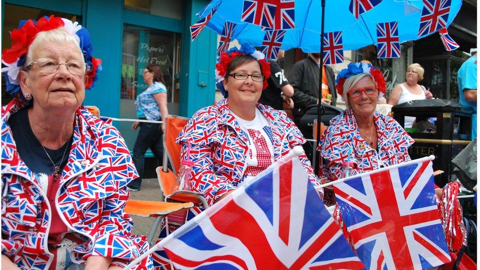 Rachel, Linda and Agnes are each dressed in union jack t-shirts, jumpers and trousers, and holding union jack flags