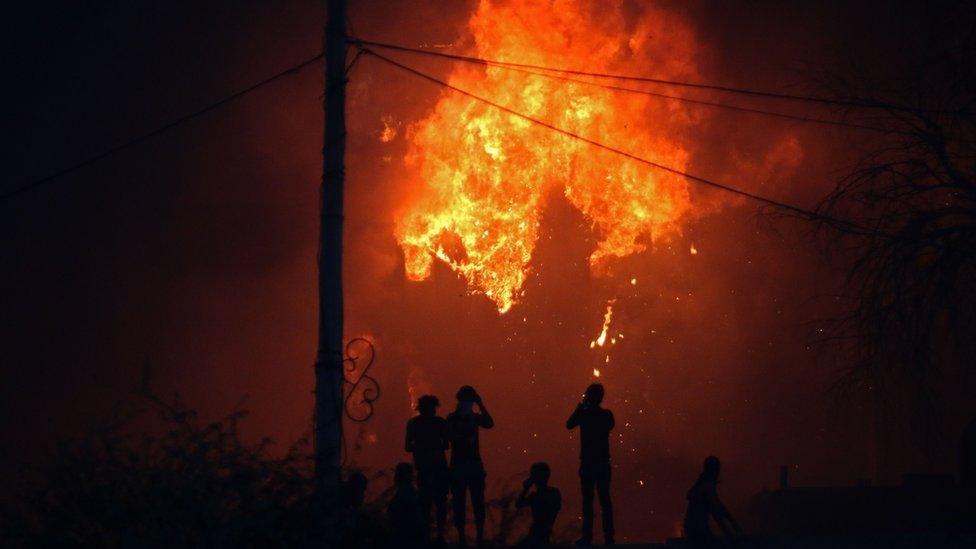 Protesters watch an official building in flames in Basra, Iraq, 6 September 2018