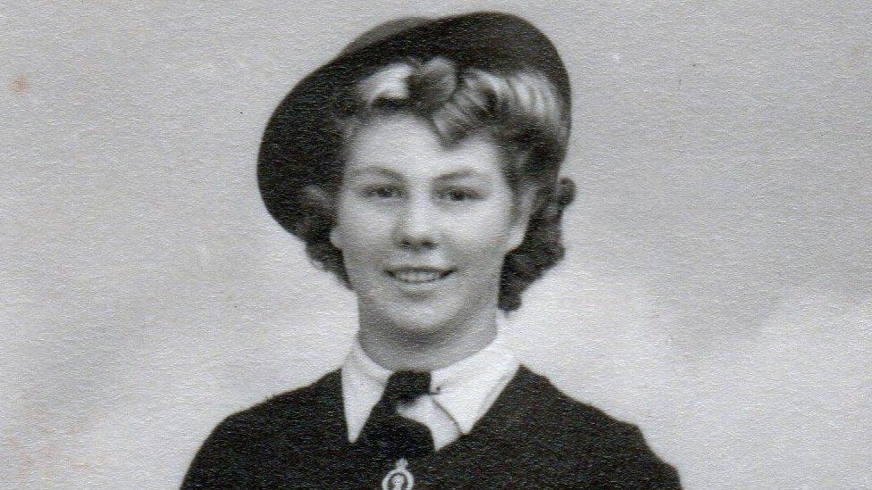 Head shot of a woman with dark hair wearing a uniform with a wide-brimmed hat