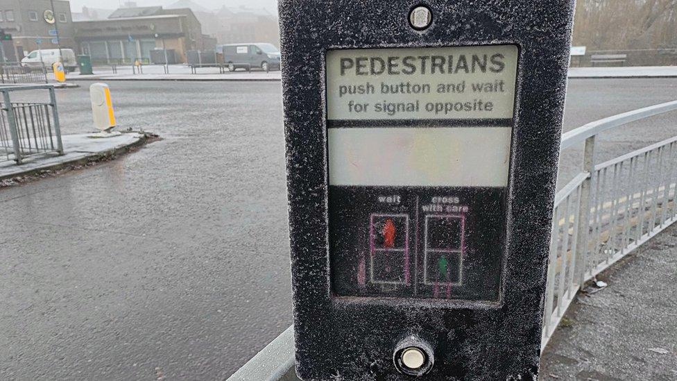 A pedestrian crossing control coated in ice and snow