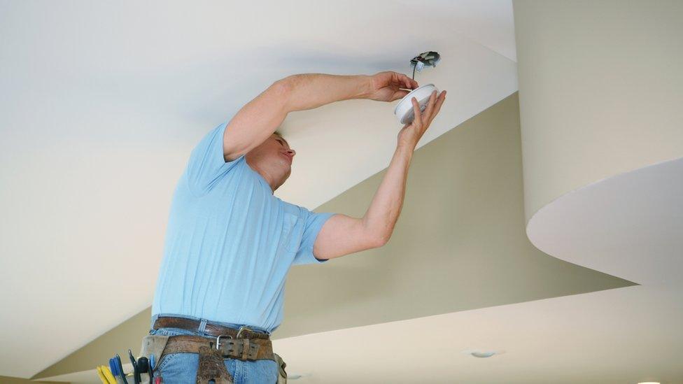 Electrician fitting a smoke alarm