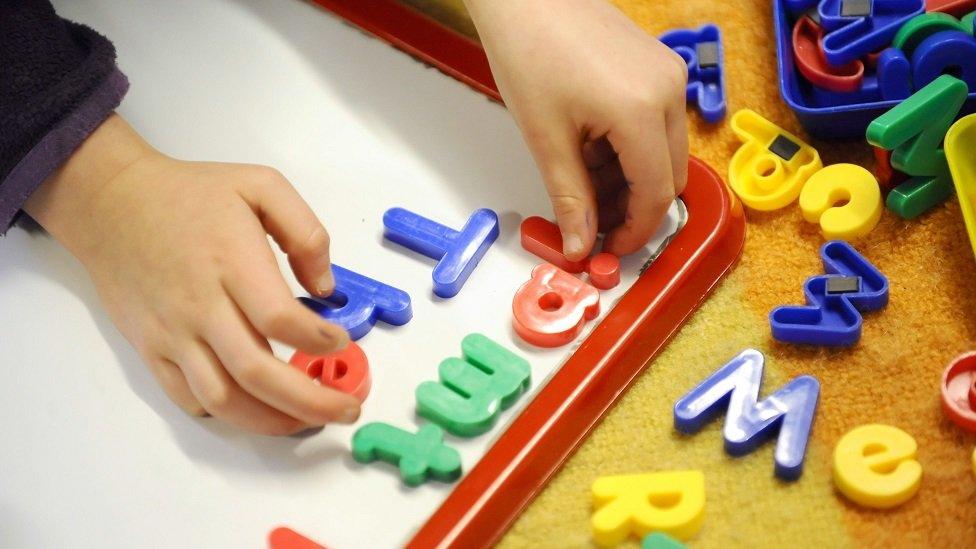 A file photo showing a child's hands arranging colourful letters on a magnetic whiteboard