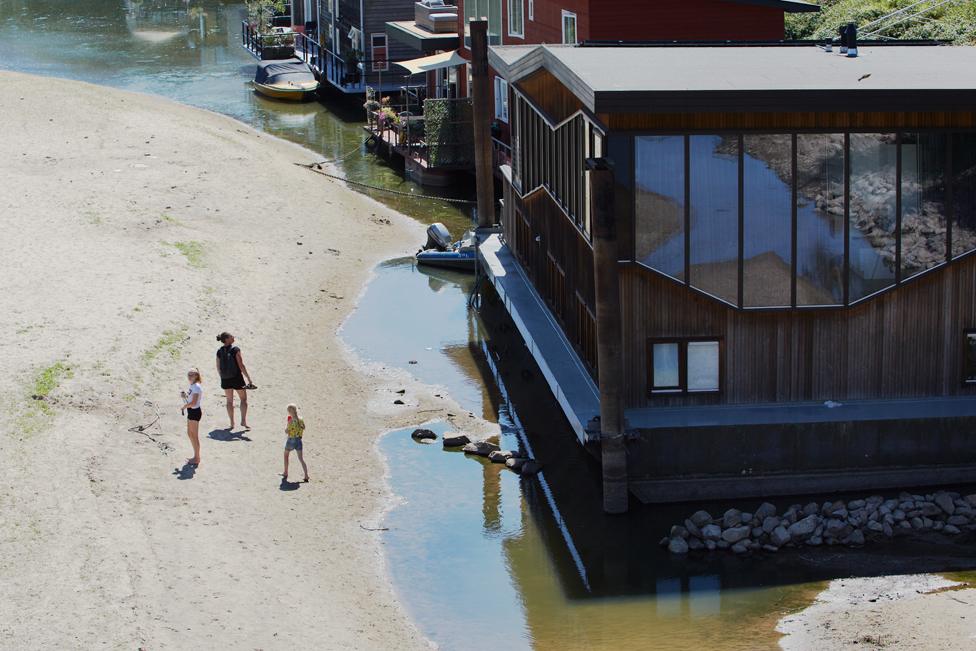 People walk near boat houses on the banks of the Waal River on August 10, 2022 in Nijmegen, Netherlands.