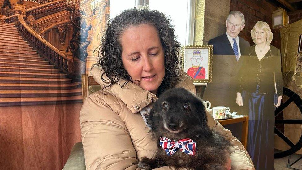 A woman holding a daschund wearing a Union Jack collar