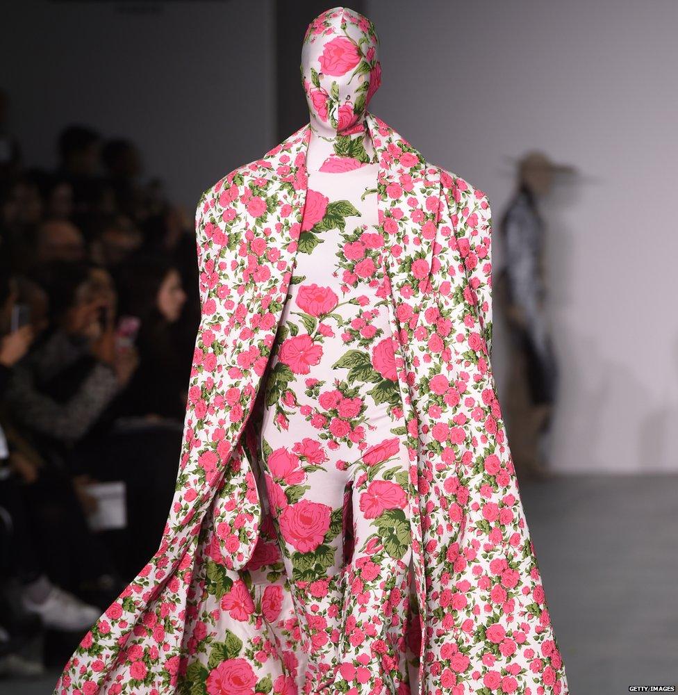 A model wears an outfit entirely covered in pink flowers