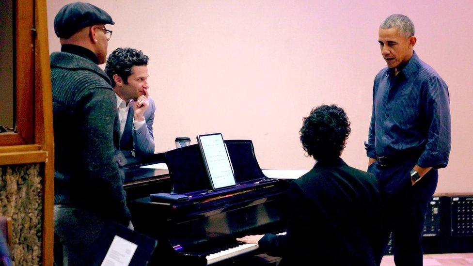 Four men stand around a piano. One of them is former US President Barack Obama