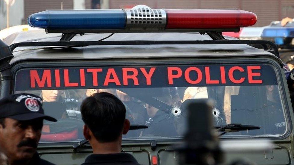 Pakistani security officials inspect a vehicle with bullet holes of military policemen after an attack in restive Karachi (01 December 2015)