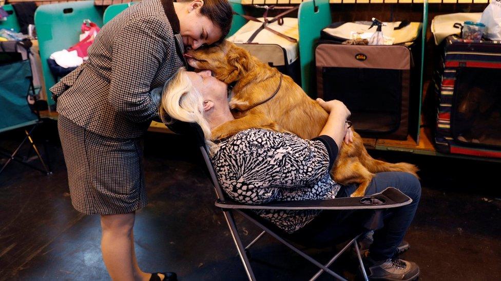 A pair of women hug their dog