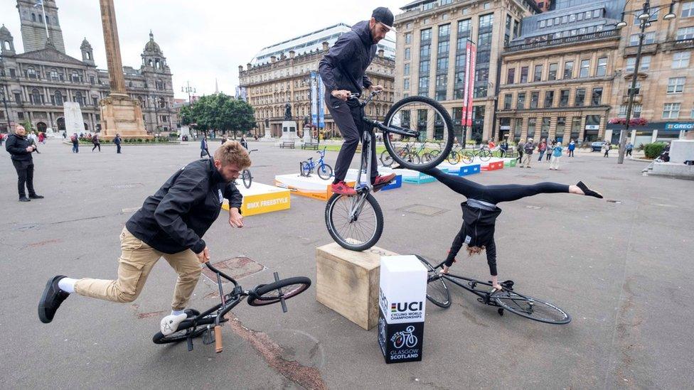 Three people doing tricks on BMX bikes