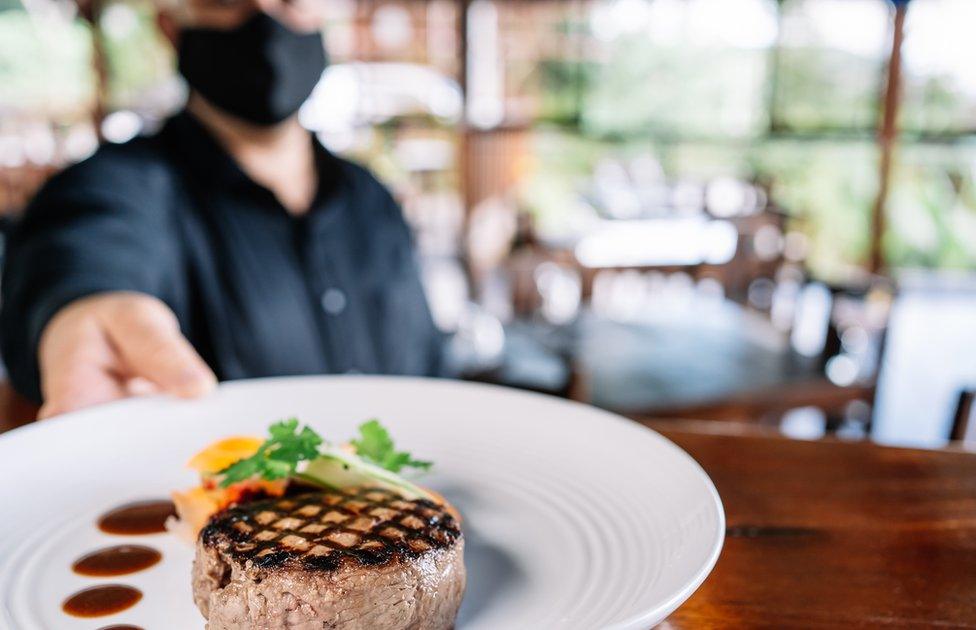 Masked waiter holding plate of food