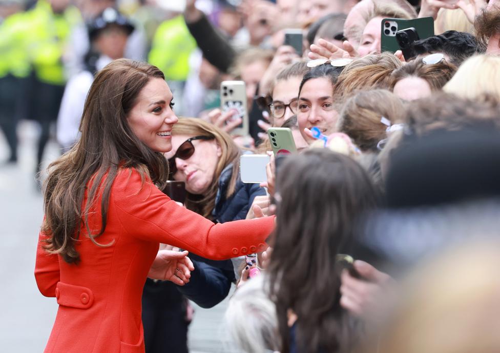 Catherine, Princess of Wales, smiles and takes pictures with well-wishers during a visit to the Dog & Duck Pub to speak to members of staff to hear how it is preparing for the Coronation.