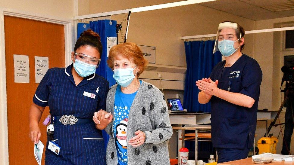 Margaret Keenan holding hands with the nurse