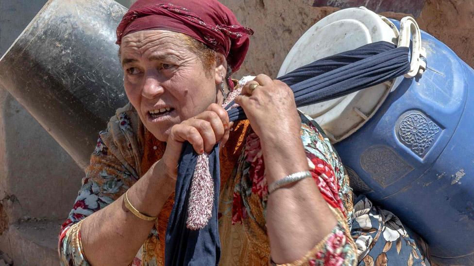 An earthquake survivor carries salvaged belongings