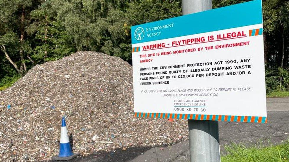 A fly-tipping sign by the pile of rubbish