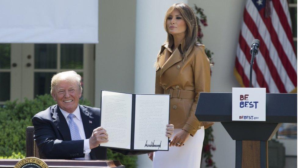 US President Donald Trump holds the proclamation, Melania Trump stands next to him