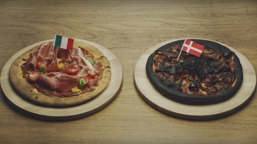 Two pizzas - one perfectly cooked and topped with the Italian flag, the other burnt to a crisp and topped with the Danish flag