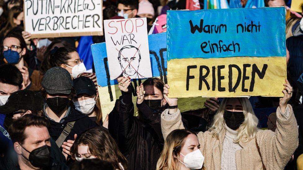 Supporters of Ukraine demonstrate with cardboards reading "why not just peace", "stop war" and "Putin, war criminal" in Berlin, Germany, 27 February 2022.