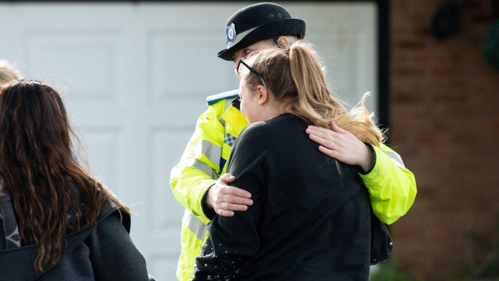 A police officer consoles a grieving woman at the scene