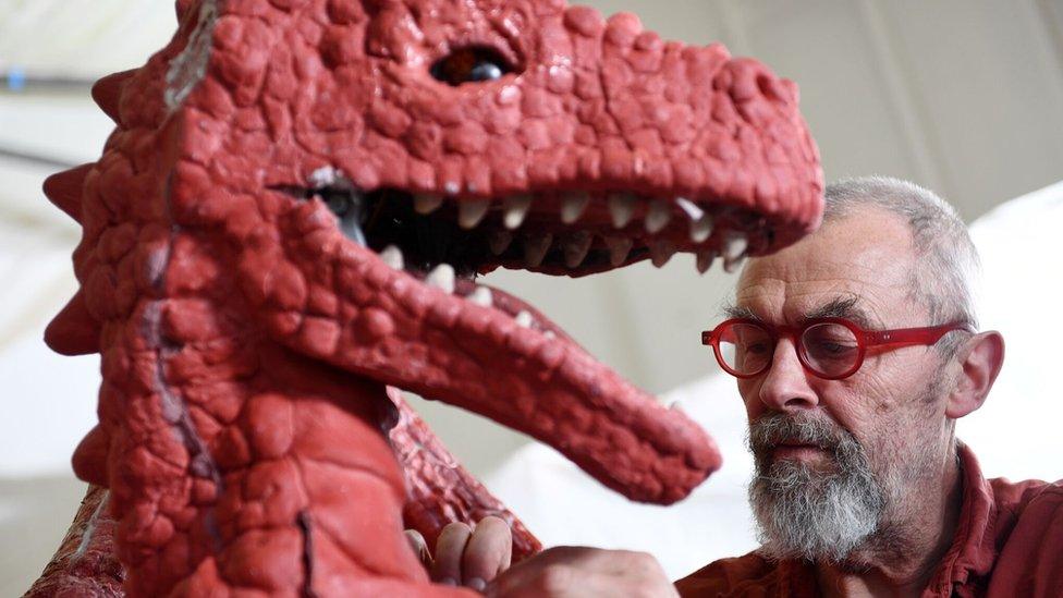 An artist working on a dragon sculpture